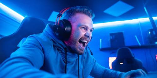 Jugador de esports con audífonos celebrando frente a la pantalla