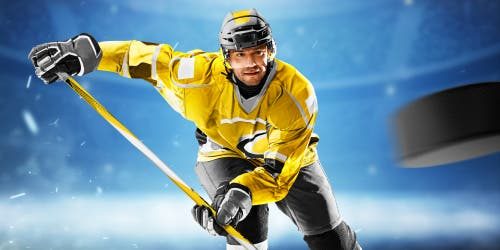 Jugador de hockey sobre hielo con uniforme amarillo y el disco en primer plano